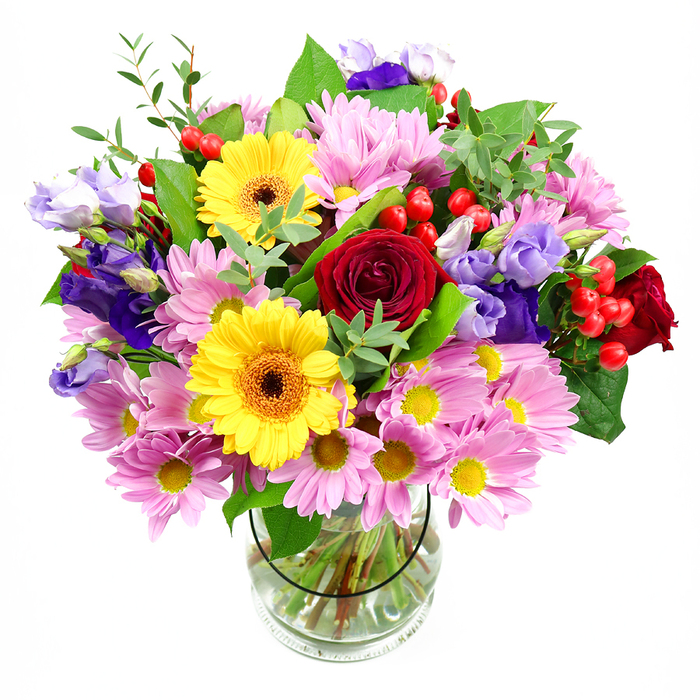 A lush, generously proportioned floral arrangement rises confidently from a clear glass vase, its colours and textures showcased against a pristine white background. At the heart of the bouquet, deep red roses form a luxurious core, their tightly layered, velvety petals creating a sense of romance and timeless elegance. Nestled alongside them, two golden yellow gerbera daisies with dark brown-orange centres shine brightly, like cheerful focal points drawing the eye. Around these central blooms spreads a soft halo of pink daisies and chrysanthemums, each flower generously petalled, with delicate yellow centres that introduce a gentle, uplifting glow. Woven between the pinks and reds are graceful stems of lisianthus in tones of purple and lavender; their bell-shaped flowers and buds curve lightly, adding a sophisticated coolness and a slightly wild, garden-grown charm. Scattered throughout, rounded red hypericum berries bring a modern accent and an almost tactile, bead-like texture that contrasts beautifully with the fluffier petals. All of this is cradled by layers of greenery in different shades - broad, darker leaves that provide structure, and slender, light-green sprigs that soften the edges and echo the freshness of local parks around New Southgate, such as Arnos Park and Oak Hill. The transparent vase reveals a neat grid of stems resting in clear water, reflecting the careful craftsmanship of an experienced florist. This bouquet feels perfect for milestone moments - perhaps a promotion celebrated in an office near New Southgate station or a birthday in a family home off Friern Barnet Road - bringing a sense of joy, care, and thoughtful generosity to any room.